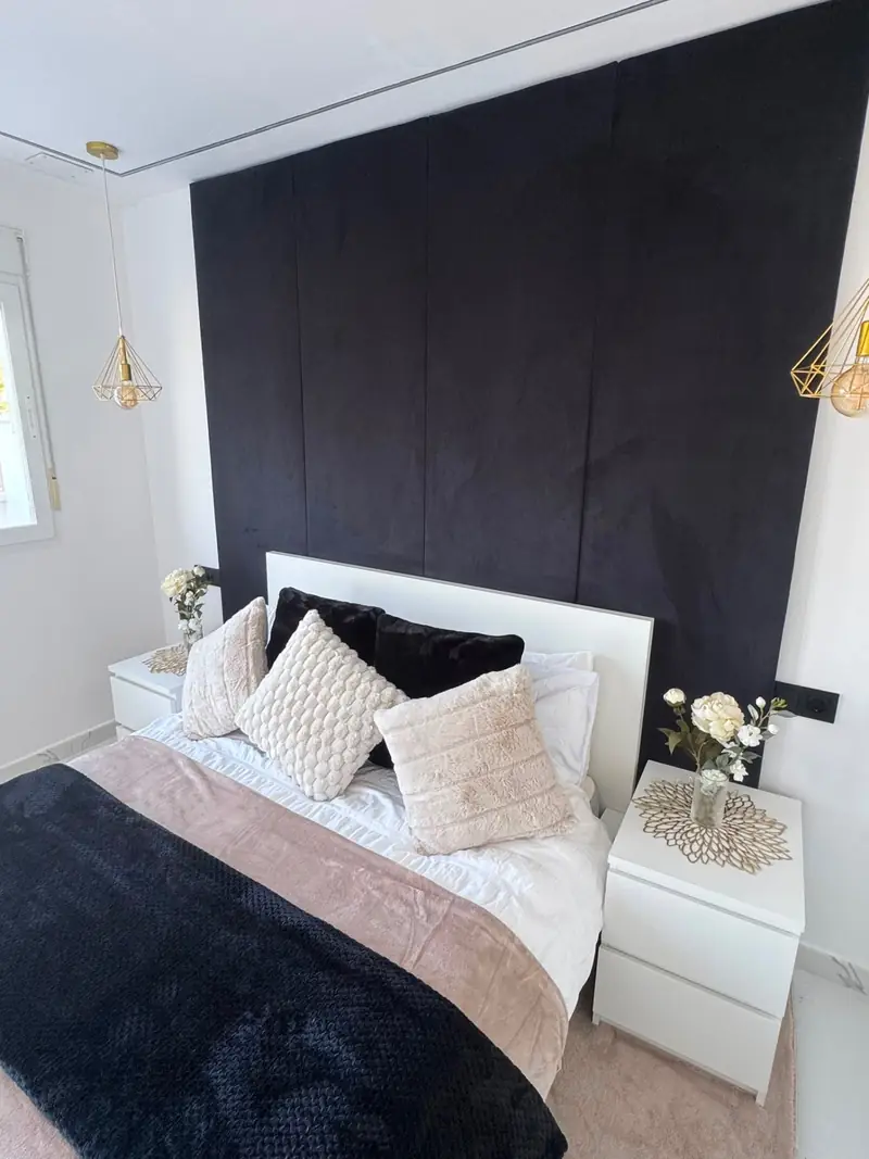 Master bedroom with black velvet feature wall, twin gold pendant lights and styled bedside tables