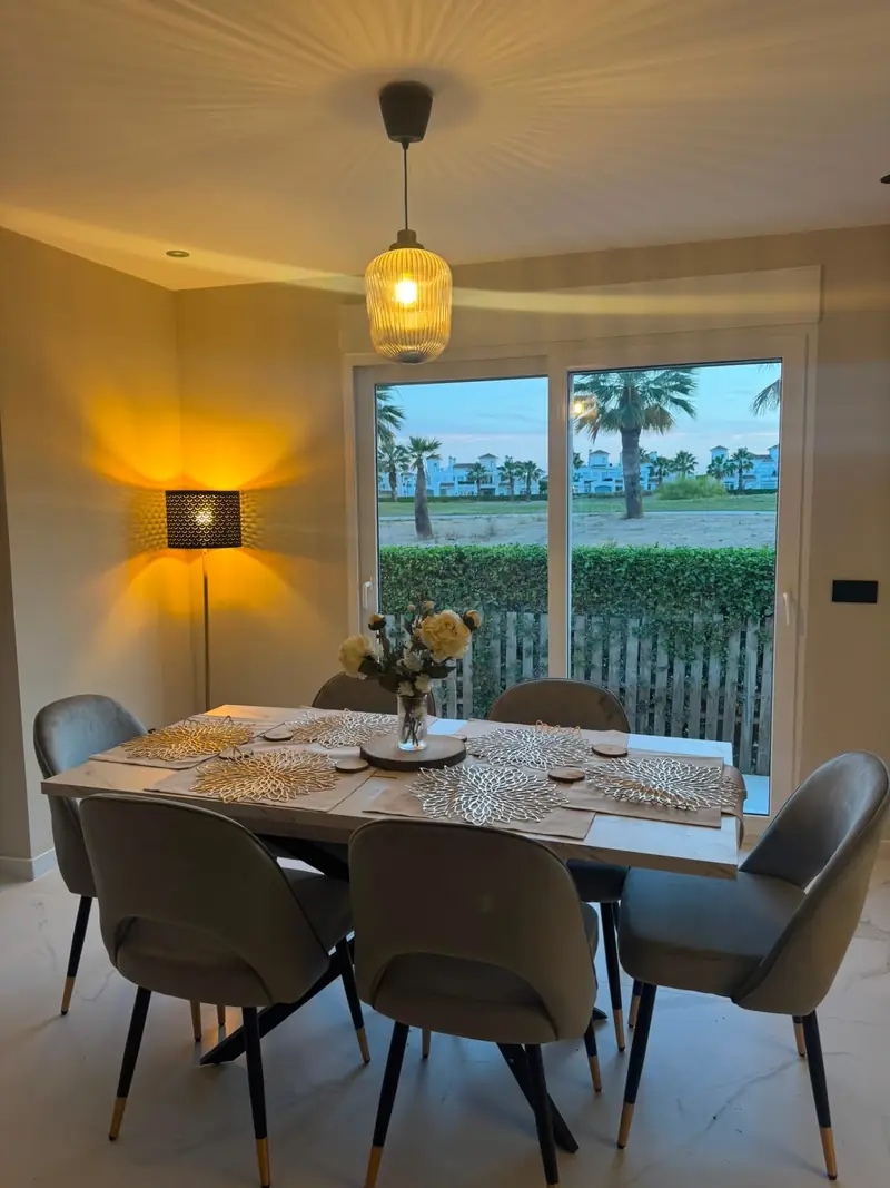 Dining table set for six with pendant lighting and golden-hour view over the golf course